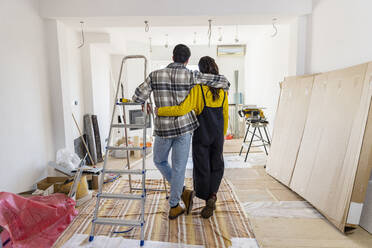 Young couple with arms around looking at new home - EIF03323