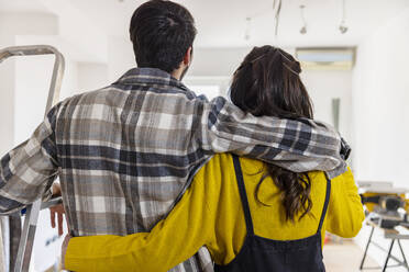 Man with arm around girlfriend looking at room being renovated - EIF03324