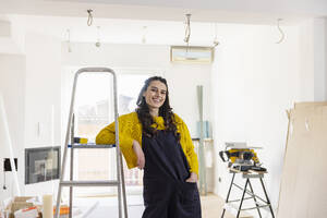 Lächelnde Frau lehnt auf einer Leiter in ihrem neuen Zuhause - EIF03331