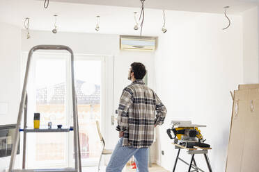 Young man looking at living room being renovated - EIF03340