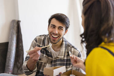 Glücklicher Mann isst Sushi mit Freundin im Wohnzimmer - EIF03344