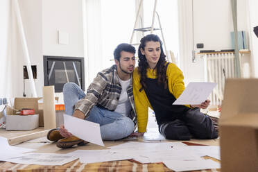 Young couple discussing over floor plan at new home - EIF03352