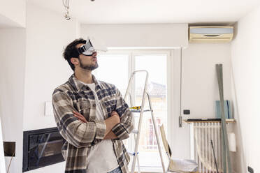Mann mit verschränkten Armen und VR-Brille bei der Renovierung seines Hauses - EIF03363