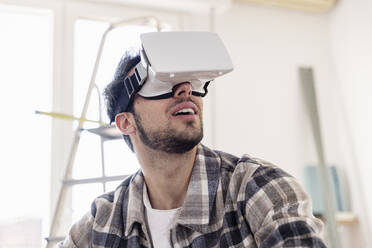 Young man watching through VR glasses at new home - EIF03365