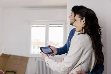 Young couple holding tablet PC at new home - EIF03386