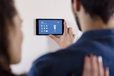 Heterosexuelles Paar nutzt die IOT-Home-App über einen Tablet-Computer in der neuen Wohnung - EIF03391