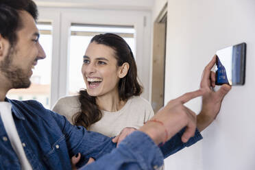 Cheerful woman talking with boyfriend holding tablet PC at new home - EIF03392