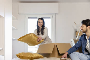 Young couple unpacking cardboard boxes in bedroom and moving into new home - EIF03398