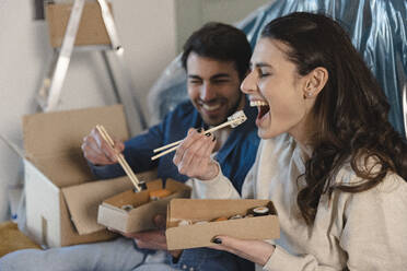 Junge Frau isst Sushi mit ihrem Freund und zieht in ein neues Haus um - EIF03413
