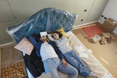 Mann mit VR-Brille auf dem Bett liegend bei Freundin im Schlafzimmer - EIF03414