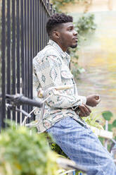 Junger Mann sitzt auf einem Fahrrad am Zaun - IFRF01543