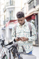 Mann mit Mobiltelefon an einer Fahrradabstellanlage - IFRF01556