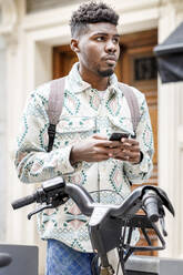 Mann mit Smartphone an einer Fahrradabstellanlage - IFRF01557