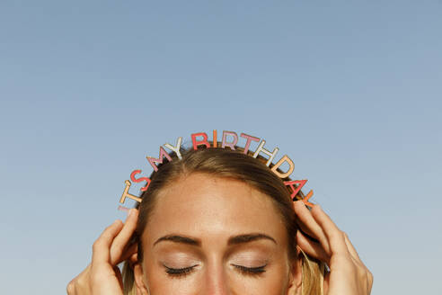 Cheerful woman with a birthday headband on the beach, close up - TYF00101