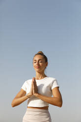 Woman in a meditation pose on the beach - TYF00104