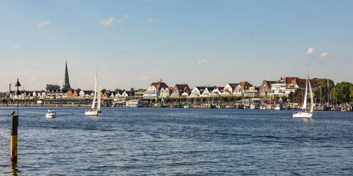 Deutschland, Schleswig-Holstein, Lübeck, Boote auf der Trave mit Stadthäusern im Hintergrund - WDF06832