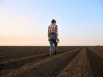 Landwirt untersucht gepflügtes Feld bei Sonnenuntergang - NOF00445