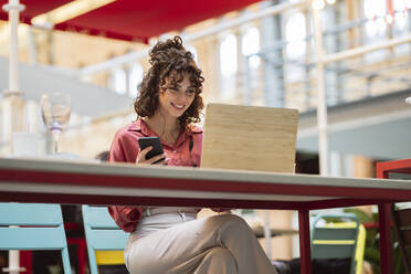 Lächelnde Geschäftsfrau, die in einem Café am Laptop arbeitet - JCCMF05357