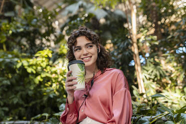 Lächelnde Frau mit Einweg-Kaffeebecher im Garten - JCCMF05368