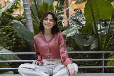 Smiling woman sitting in garden - JCCMF05375