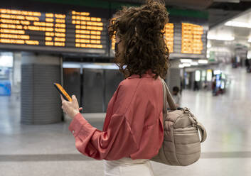 Junge Frau mit Smartphone am Bahnhof stehend - JCCMF05380