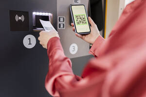 Frau scannt QR-Code am Fahrkartenautomaten mit ihrem Smartphone am Bahnhof - JCCMF05393