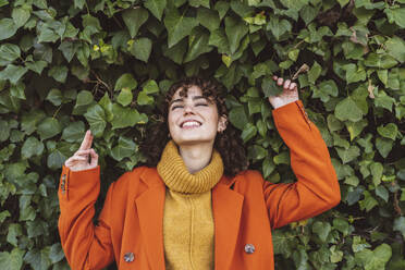 Young woman leaning on ivy wall - JCCMF05411