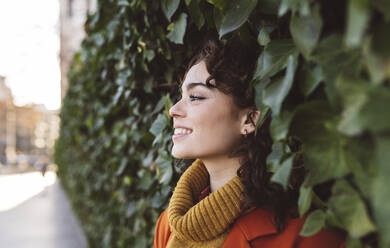 Contemplative woman leaning on plants - JCCMF05413