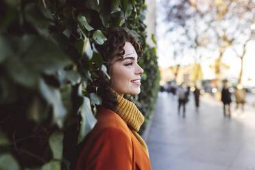 Young woman leaning on plants - JCCMF05414