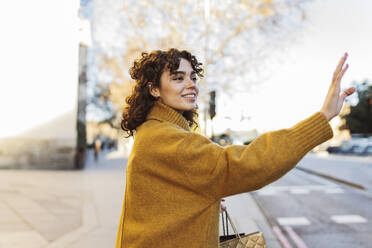 Young woman hailing ride on street - JCCMF05440