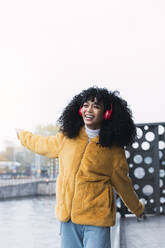 Cheerful woman dancing and listening music through headphones - PNAF03274