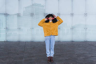 Young woman listening music through headphones on footpath - PNAF03302