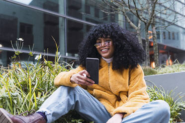 Young woman using smart phone by plants - PNAF03308