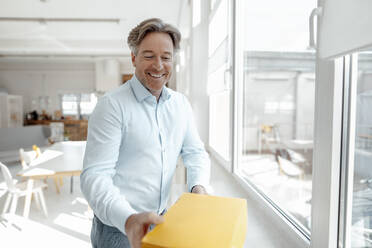 Happy businessman receiving box in office - KNSF09245