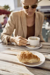 Woman having coffee at sidewalk cafe on sunny day - SSCF00815