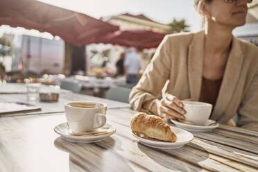 Frau mit Kaffeetasse in einem Straßencafé an einem sonnigen Tag - SSCF00816