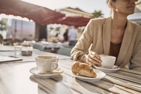 Frau mit Kaffeetasse in einem Straßencafé an einem sonnigen Tag - SSCF00816