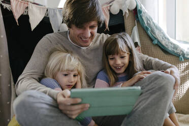 Father with daughters watching video on tablet computer - TYF00105