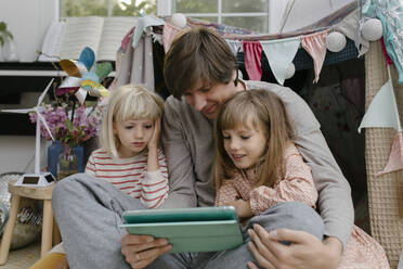 Father with daughters watching video on tablet computer - TYF00106