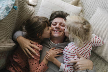 Töchter küssen den Vater, der zu Hause auf dem Kopfkissen liegt - TYF00110
