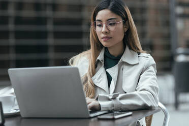 Freiberufler mit Brille und Laptop in einem Straßencafé - JSRF01856