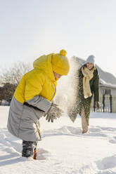 Lächelnde Mutter und Sohn spielen mit Schnee im Winter - SEAF00555
