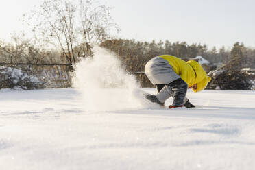 Verspielter Junge beim Schneeschaufeln im Garten im Winter - SEAF00558