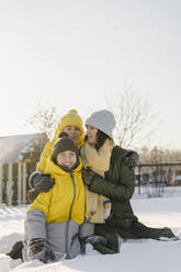 Lächelnde Jungen mit Mutter im Schnee sitzend im Winter - SEAF00561