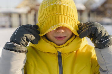 Junge bedeckt Augen mit gelber Strickmütze im Winter - SEAF00564