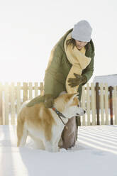 Frau mit Hund im Tiefschnee stehend im Winter - SEAF00566