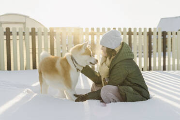 Woman with pet dog at snowy garden in winter - SEAF00567