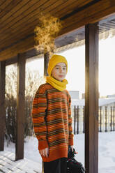 Junge in warmer Kleidung auf der Veranda im Winter - SEAF00570