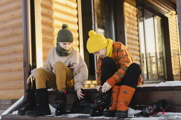 Jungen mit Schlittschuhen auf der Veranda eines Hauses im Winter - SEAF00575