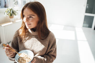 Thoughtful woman with cereal bowl at home - JOSEF07198